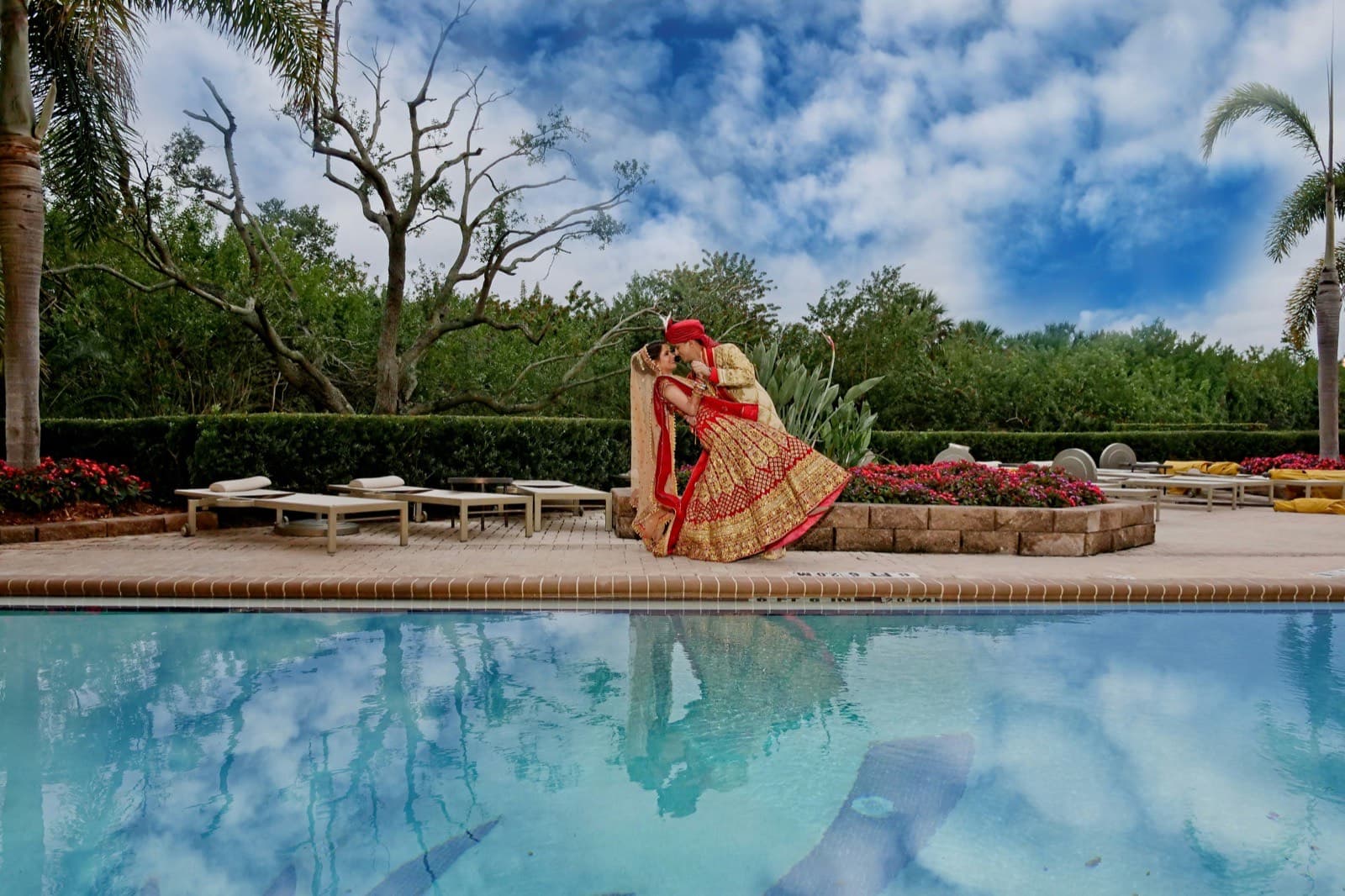 Couple in red and gold wedding attire by the water